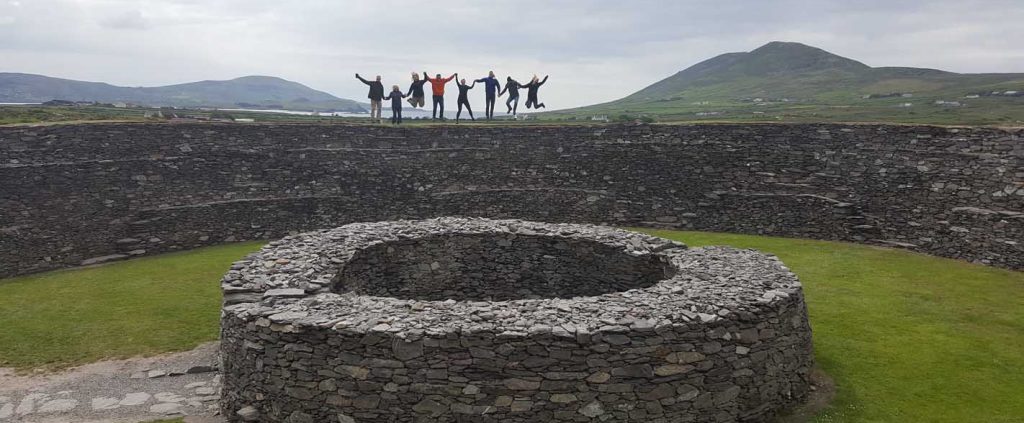 A group posing in front of an old Irish settlement
