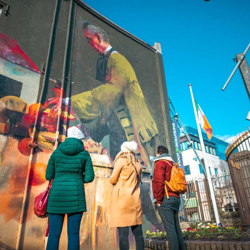 Three people looking at a mural in Cork city