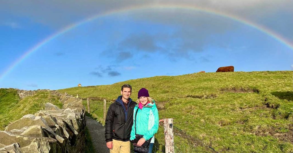 Two people posing under a rainbow